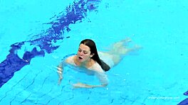 Valkopukuisessa tiukka karvainen tyttö Katy Soroka ui veden alla viehkeästi