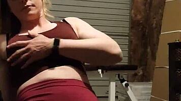 Muscular blonde milf teases in gym, undressing leggings for striptease