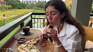Enjoying a mouthful of pizza on the street in a public cafe with beautiful teen