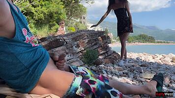 Skinny brunette strokes huge cock to cum on public beach