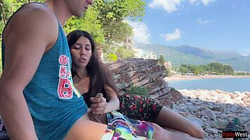 Skinny brunette strokes huge cock to cum on public beach