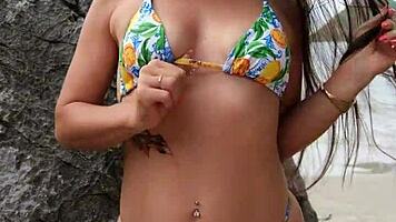 tanned petite brunette flashes bikini on tropical beach